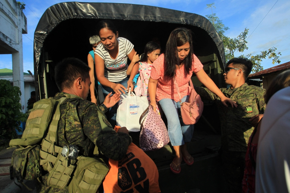 Residents get off a truck after the local government implemented a preemptive evacuation in Daraga, Albay on November 15, 2024, ahead of the landfall of Typhoon Man-Yi. Photo by Charism SAYAT / AFP