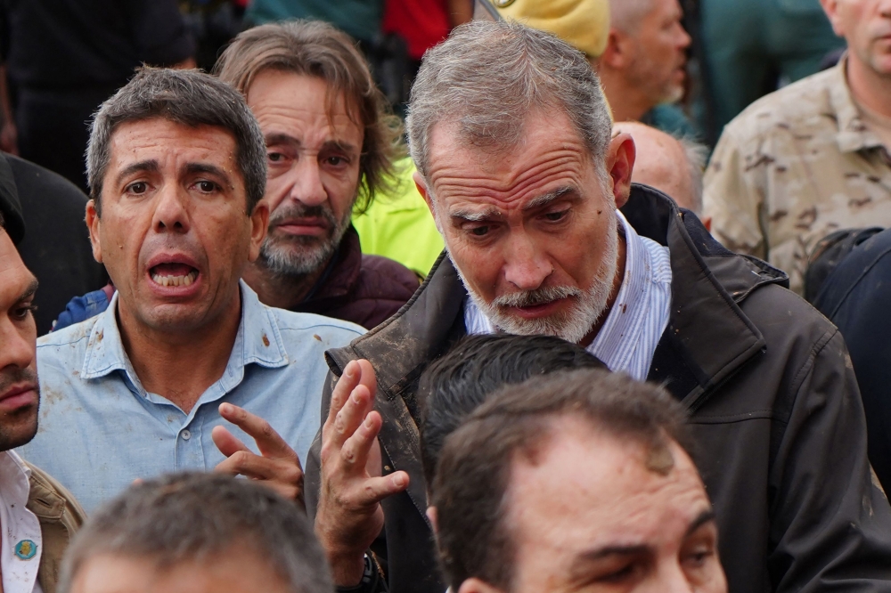 File: King Felipe VI of Spain (right) talks with a resident beside Valencia Regional President Carlos Mazon (left) as angry residents react shouting and throwing mud to the king's visit to Paiporta, in the region of Valencia, eastern Spain, on November 3, 2024, in the aftermath of devastating deadly floods. (Photo by Manaure Quintero / AFP)