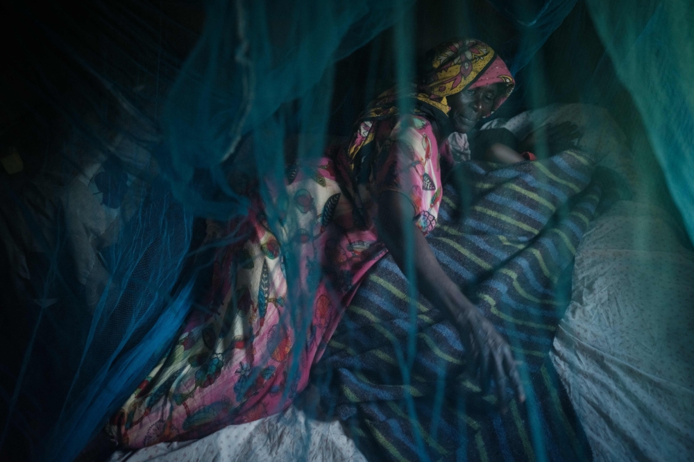 (Files) Ruth Kavere (L), 65, demonstrates to use a mosquito net with her granddaughter Faith, 3, who completed doses through the world's first malaria vaccine (RTS, S) pilot program, in Mukuli on March 7, 2023. (Photo by Yasuyoshi Chiba / AFP)