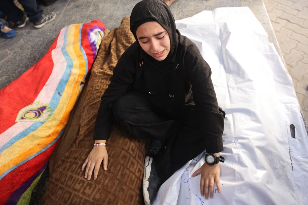 A Palestinian girl mourns over the bodies of victims of an Israeli strike the previous night south of Gaza City, at Al-Ahli Arab hospital, also known as the Baptist hospital, in Gaza City on November 22, 2024. (Photo by Omar Al-Qattaa / AFP)