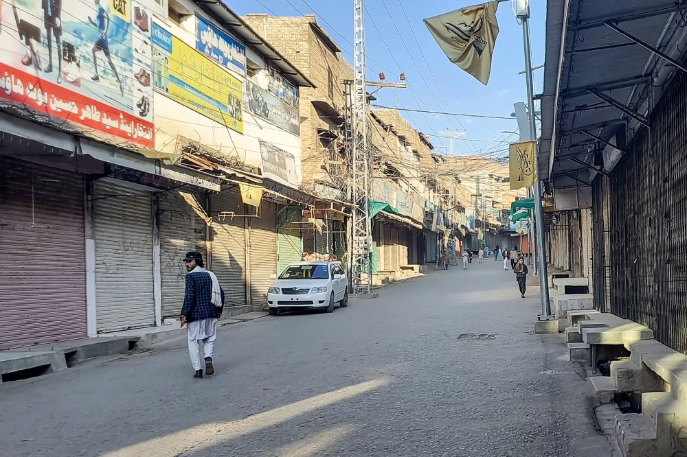 Men walk past a market closed by traders during a strike against sectarian attacks in Kurram district. (Photo by Dilawer Khan / AFP)