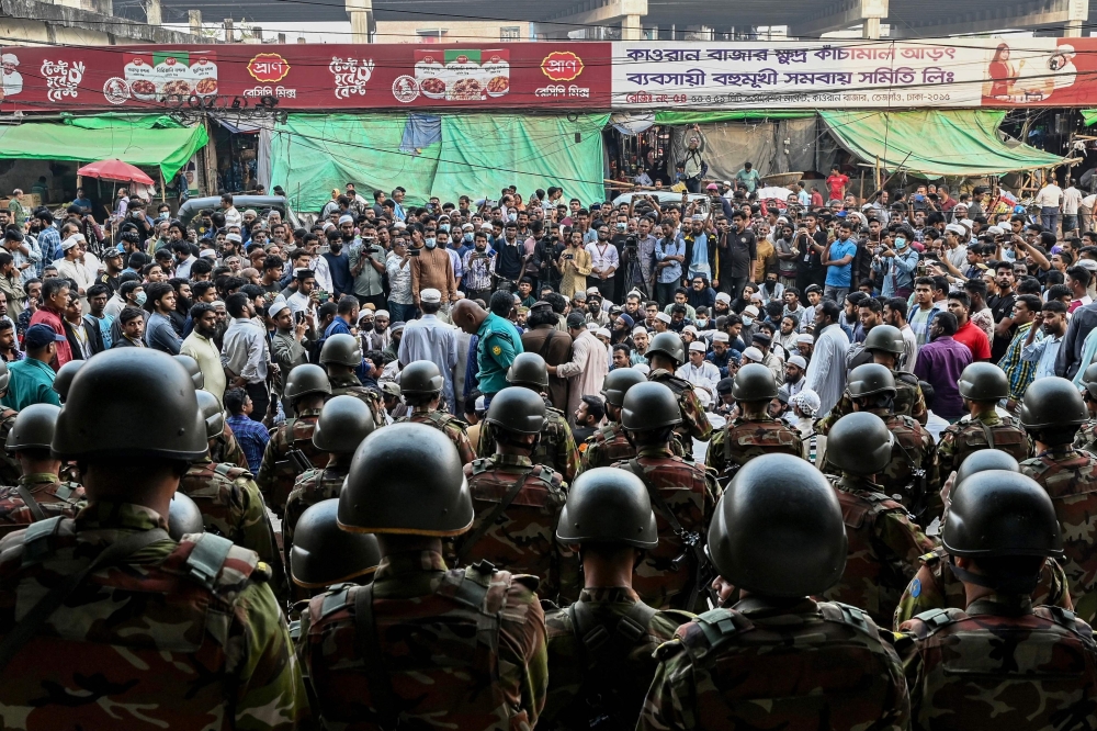 Bangladesh Army personnel stand guard as protesters stage a demonstration in front of the Bangla newspaper Prothom Alo's office in Dhaka on November 25, 2024. (Photo by Munir Uz Zaman / AFP)