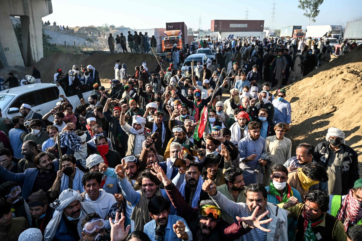 Supporters of jailed former prime minister Imran Khan's Pakistan Tehreek-e-Insaf (PTI) party shout slogans as they march towards Islamabad after clearing shipping containers placed by authorities during a demonstration demanding Khan's release, in Hasan Abdal in Punjab province on November 25, 2024. (Photo by Aamir QURESHI / AFP)
