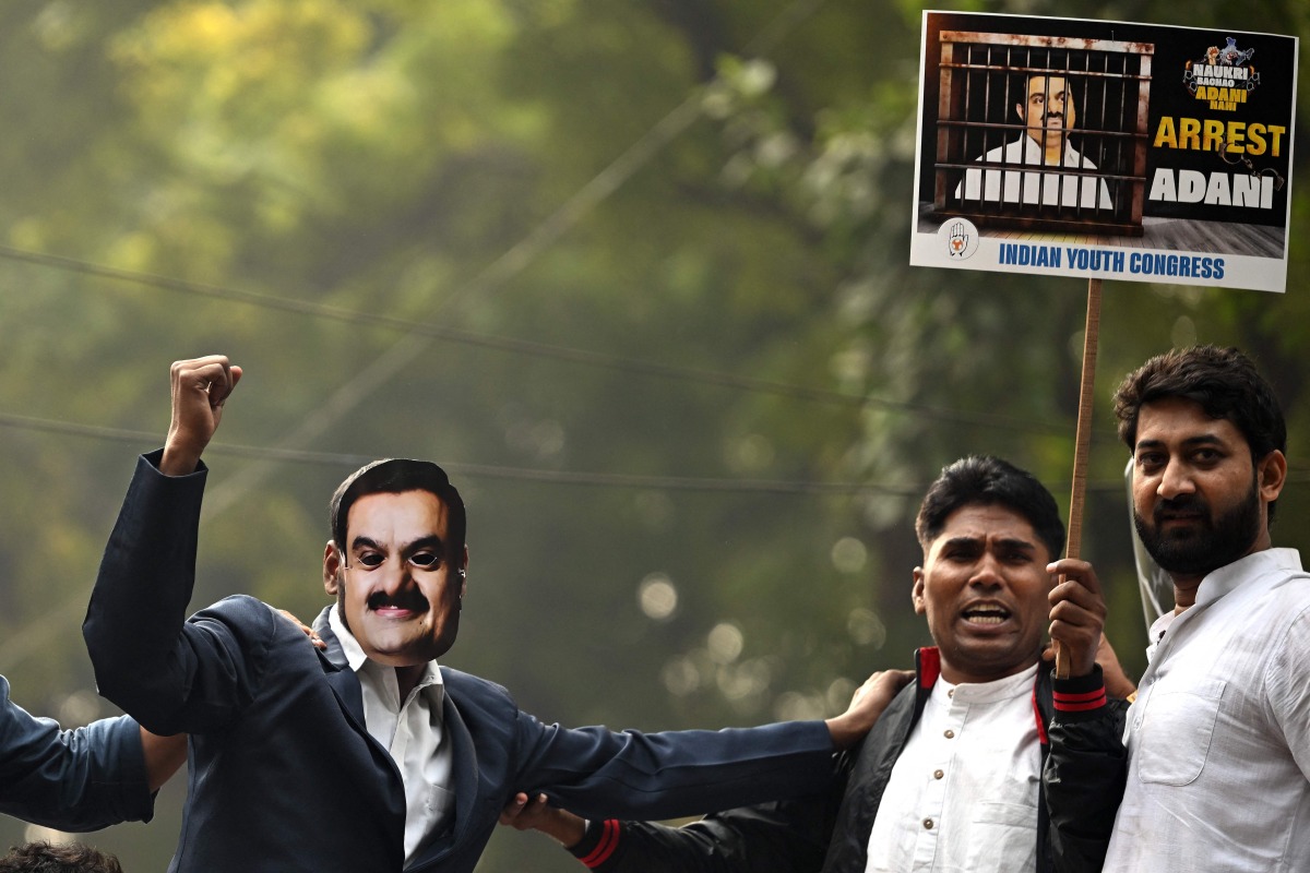 A member of the Indian Youth Congress (IYC) wearing a face cutout of Indian industrialist Gautam Adani takes part in a protest against the businessman, in New Delhi on November 25, 2024. (Photo by Sajjad HUSSAIN / AFP)
