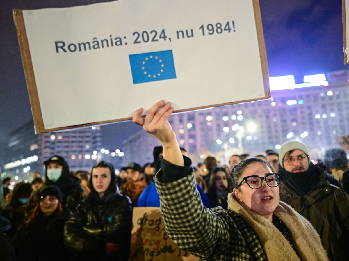 People protest in the front of the Palace of the Parliament at the Victory square in Bucharest, Romania, on November 27, 2024, with a banner reading 