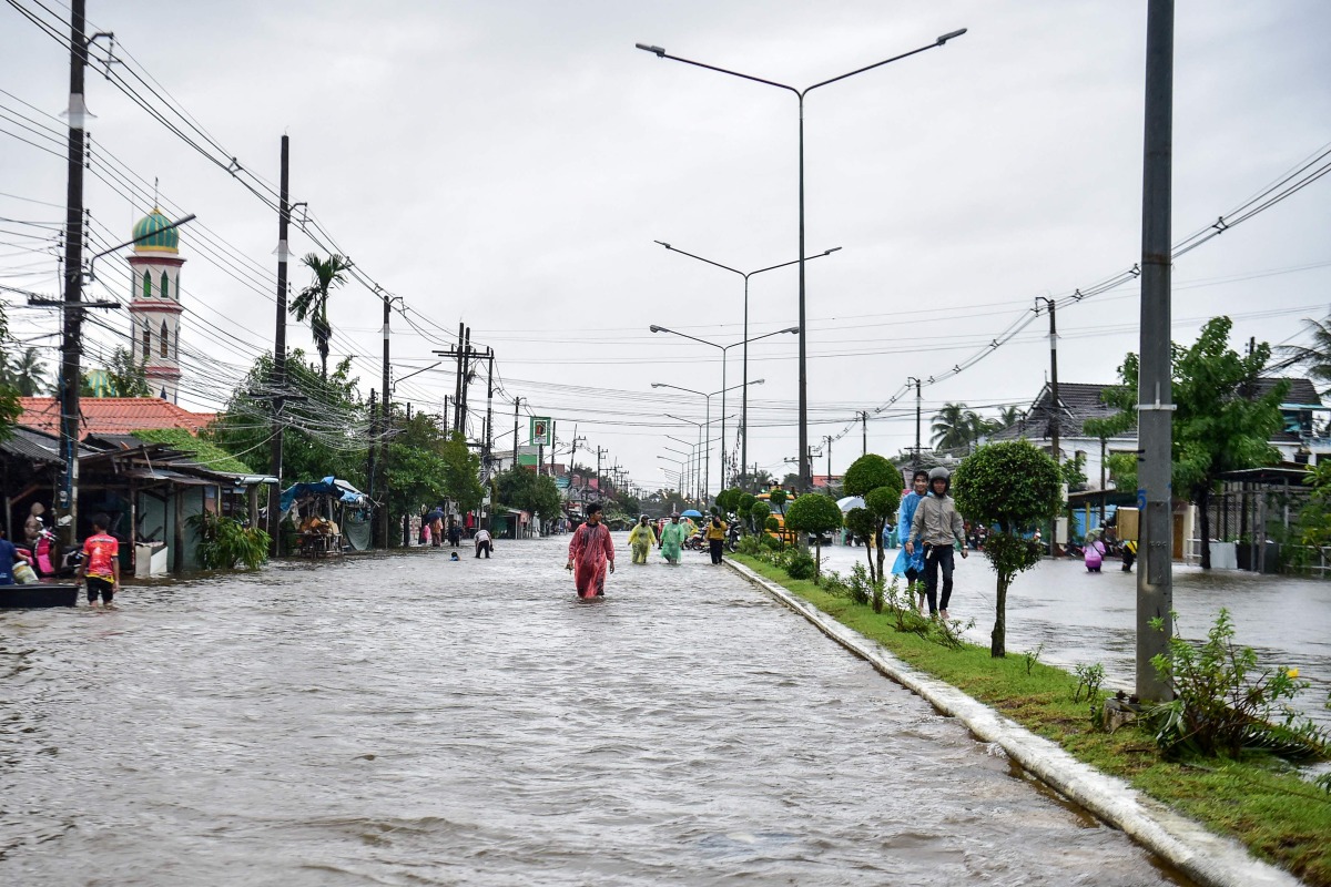 People through flood waters along a street following heavy rain in Thailand's southern province of Narathiwat on November 28, 2024. Photo by Madaree TOHLALA / AFP