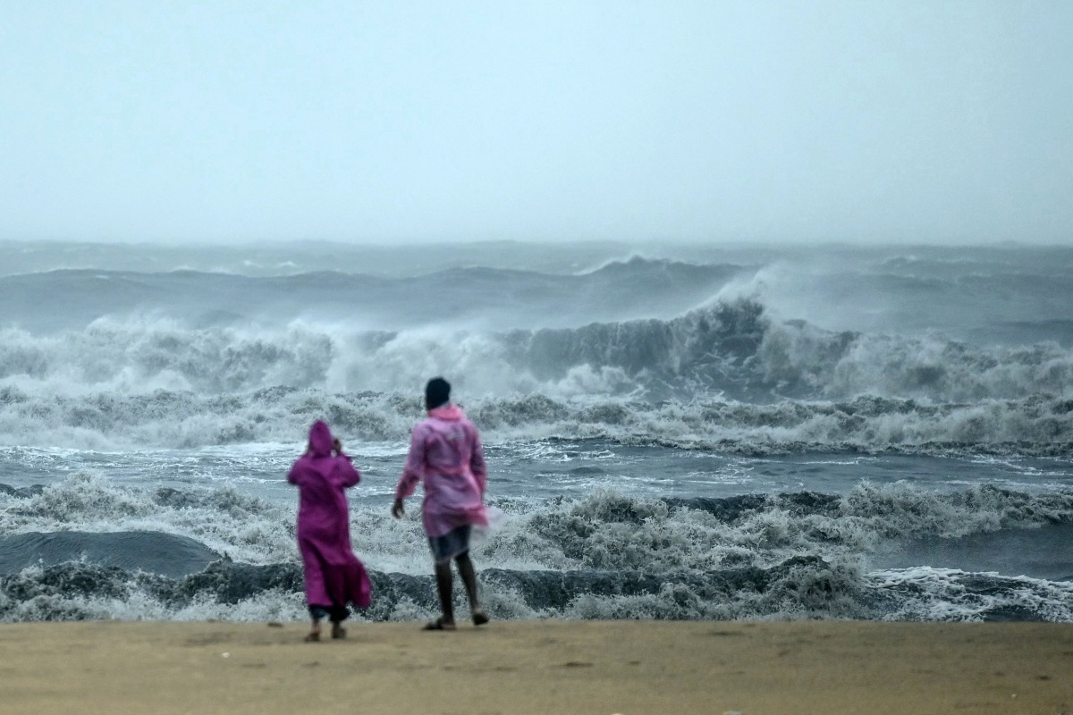 People stand ashore as they observe waves amidst heavy winds and rainfall at Marina Beach in Chennai on November 30, 2024, ahead of the landfall of cyclone Fengal in India's state of Tamil Nadu. (Photo by R. Satish BABU / AFP)
