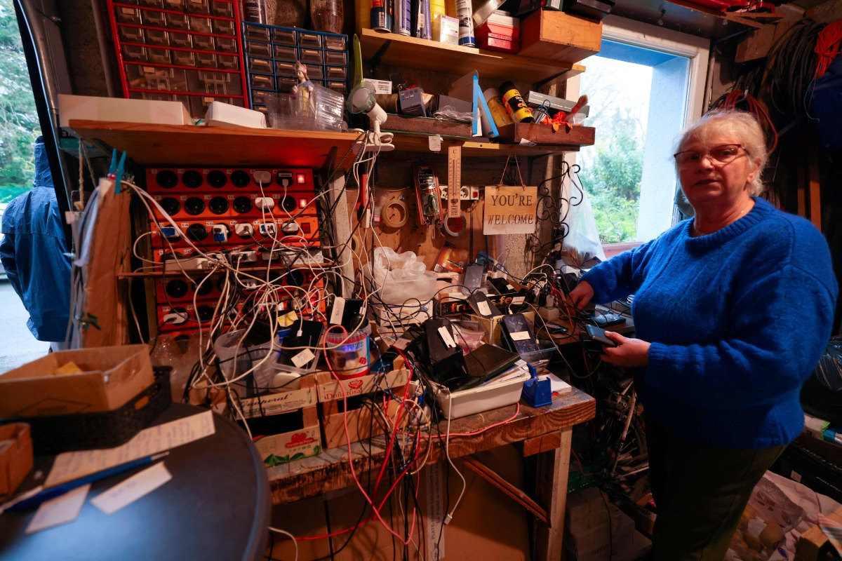 Brigitte Lips, nicknamed Mamie Charge, registers phones of migrants to be charged at her garage in Calais on November 26, 2024. (Photo by Denis Charlet / AFP)
