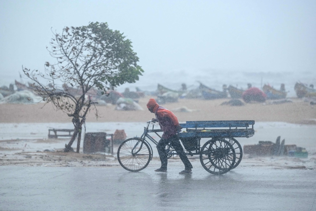 A man pulls his three-wheeler cart amid heavy wind and rainfall at the Marina Beach in Chennai on November 30, 2024, ahead of the landfall of cyclone Fengal in India's state of Tamil Nadu. Photo by R.Satish BABU / AFP