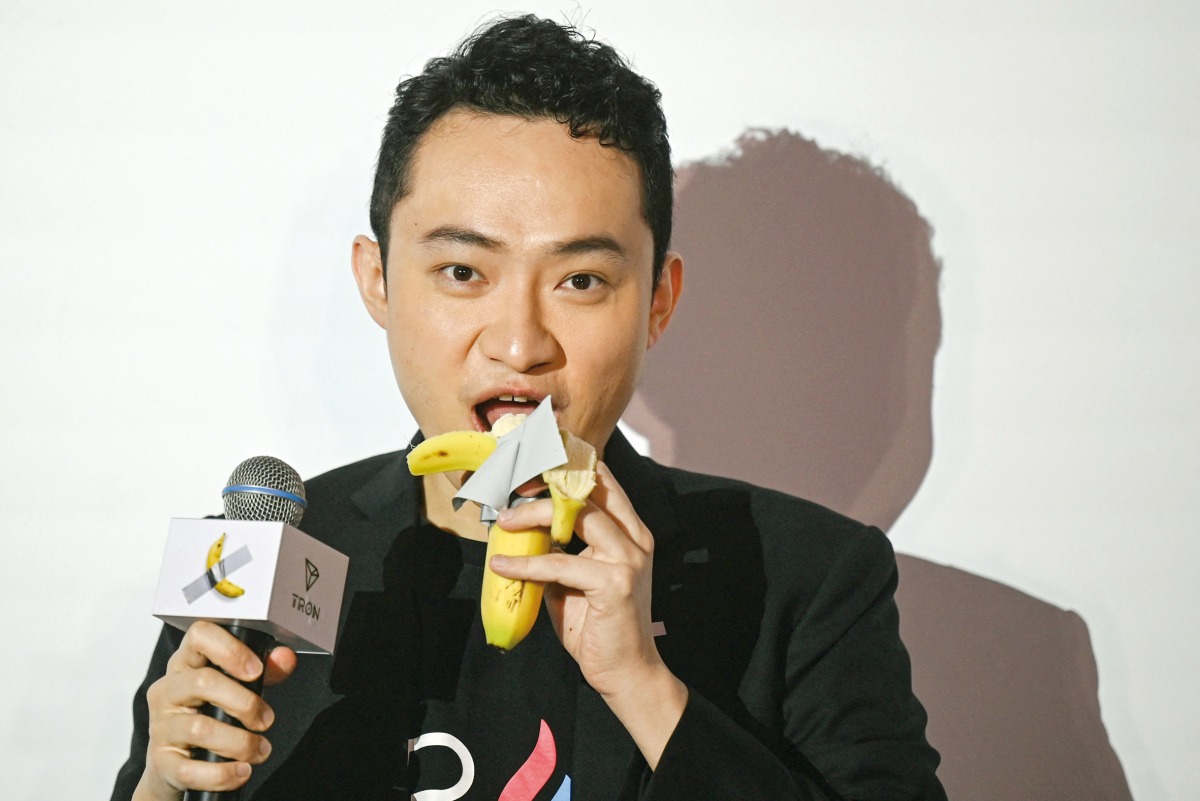 Chinese-born crypto founder Justin Sun eats banana artwork, in Hong Kong on November 29, 2024. (Photo by Peter Parks / AFP)
