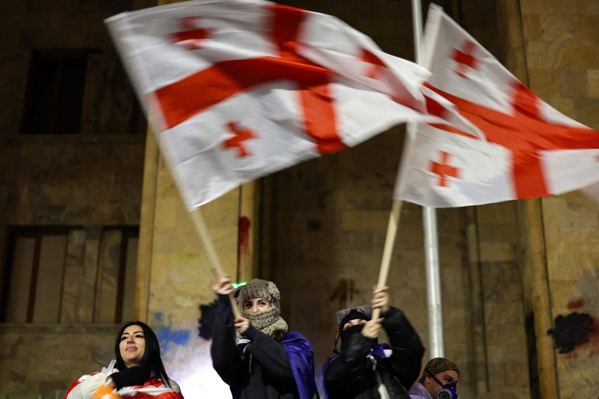 Protesters wave Georgian flags during the fifth straight night of demonstrations against the government's postponement of EU accession talks until 2028, outside the parliament building in central Tbilisi on December 2, 2024. (Photo by Giorgi ARJEVANIDZE / AFP)
