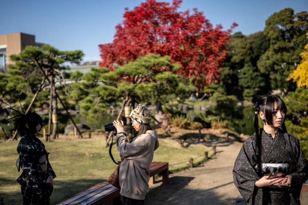 People take pictures in Kiyosumi Garden in Tokyo on December 3, 2024. (Photo by Philip Fong / AFP)