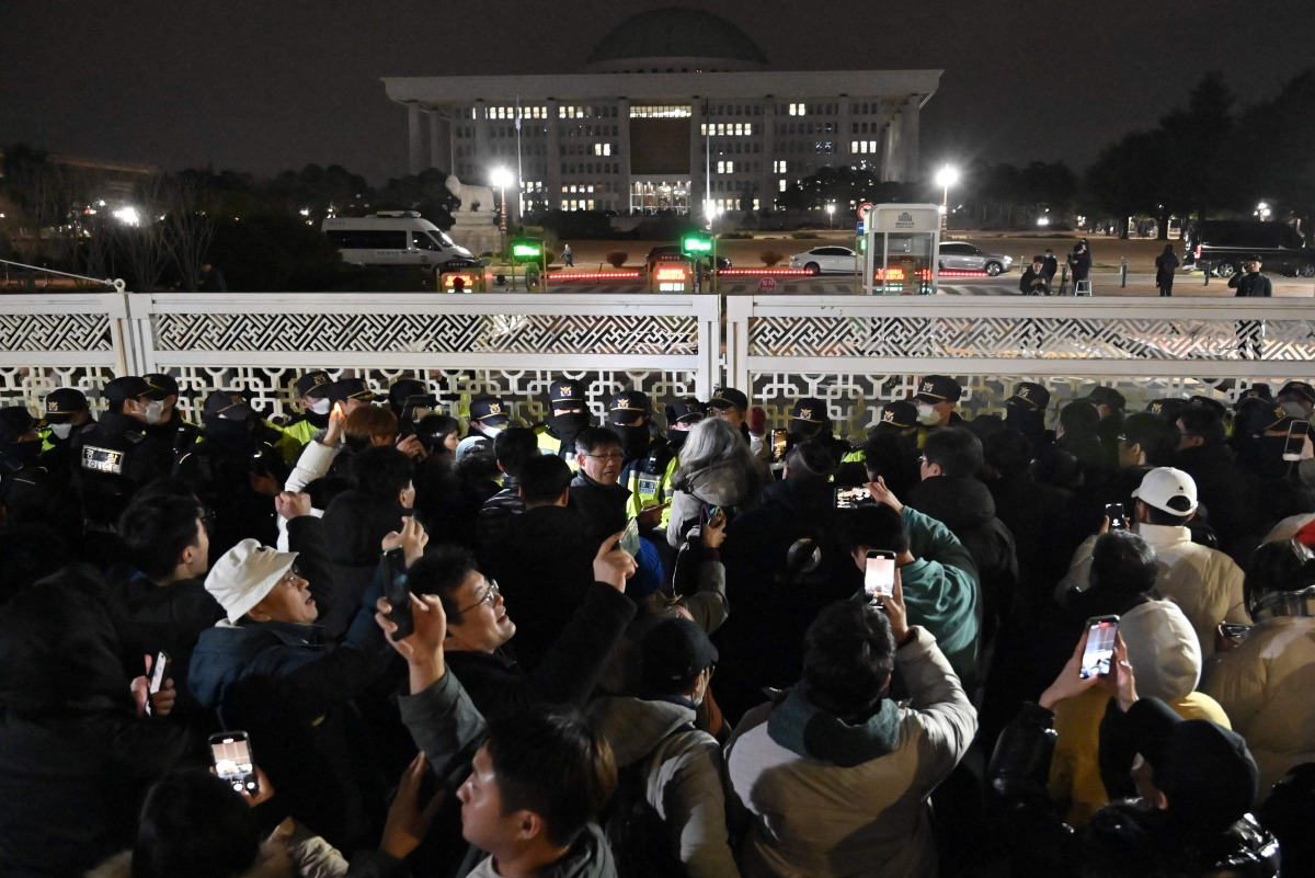 People gather in front of the main gate of the National Assembly in Seoul, South Korea on December 4, 2024, after President Yoon Suk Yeol declared emergency martial law. Photo by JUNG YEON-JE / AFP