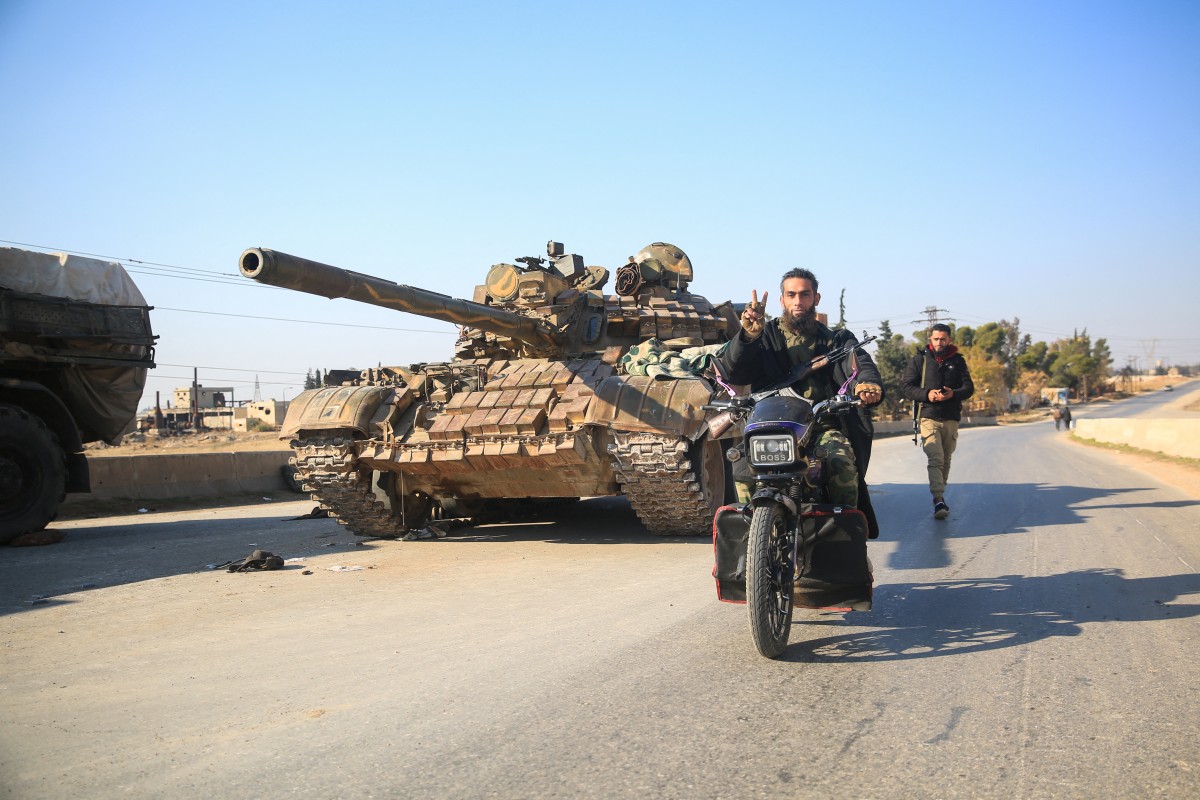 Anti-government fighters move past abandoned Syrian army military equipment and vehicles, as they reach al-Safirah town southeast of Syria's Aleppo city on December 3, 2024. Photo by Aref TAMMAWI / AFP.