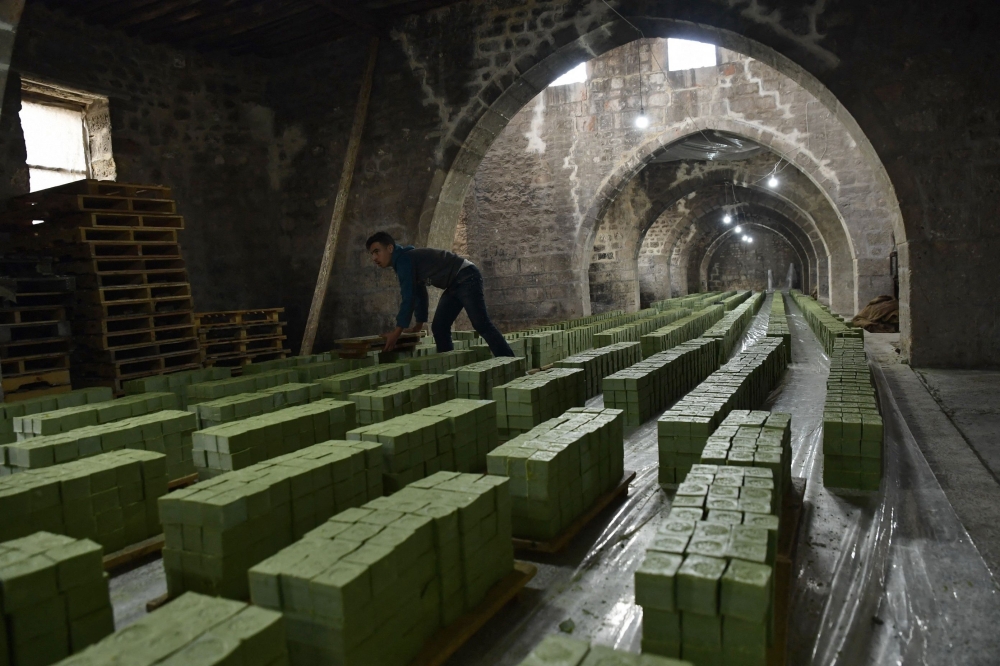 (Files) A Syrian worker stacks laurel soap at the Jbaili soap factory, an 800 year old artisanal soap manufacturer, in the old city of Syria's northern city of Aleppo on January 24, 2022. (Photo by AFP)
 