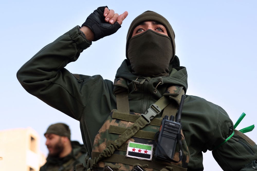 An anti-government fighter gestures in the city of Hama after forces captured the central Syrian city, on December 6, 2024. (Photo by Omar Haj Kadour / AFP)
 