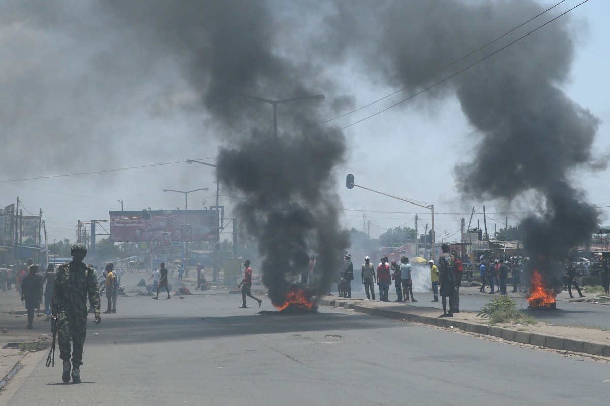 A Mozambican soldier walks away as protesters burn tyres during a demonstration against the government in Maputo on December 6, 2024.  (Photo by Amilton Neves / AFP)
