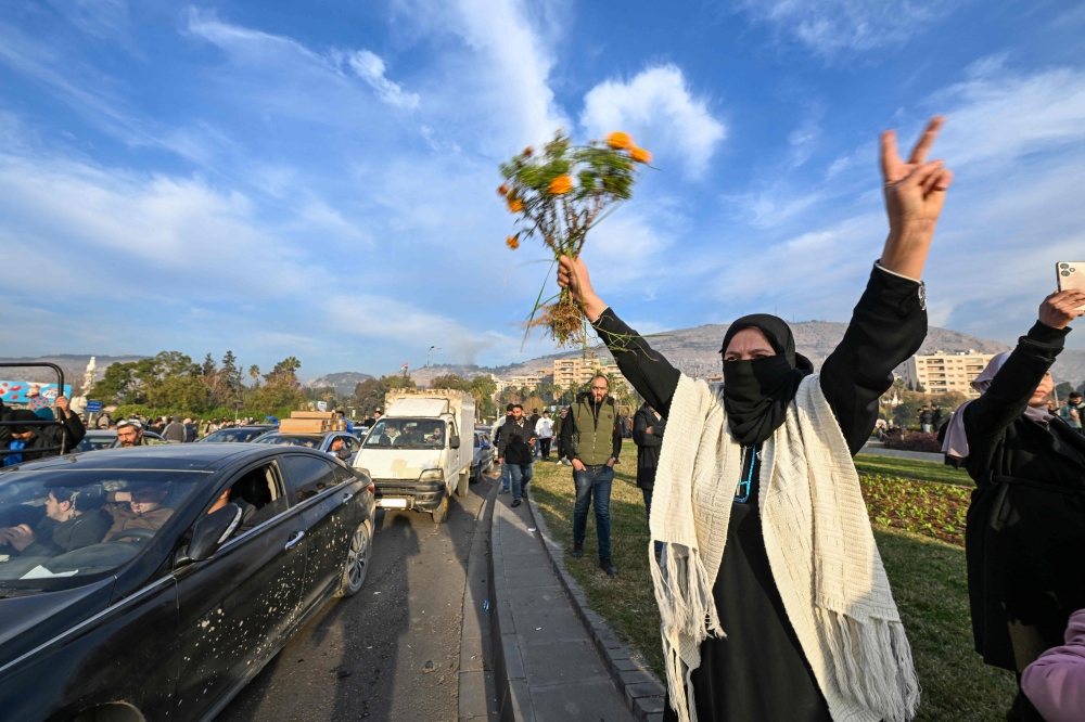 People celebrate at Umayyad Square in Damascus on December 8, 2024. (Photo by Louai Beshara / AFP)
 