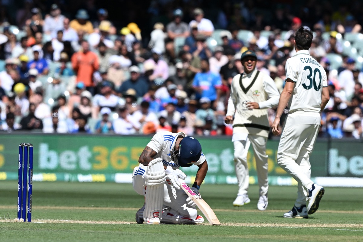 Australia's captain Pat Cummins (R) celebrates his dismissal of India's Nitish Kumar Reddy with teammate Usman Khawaja on the third day of the second Test cricket match between Australia and India at the Adelaide Oval in Adelaide on December 8, 2024. (Photo by Michael ERREY / AFP)