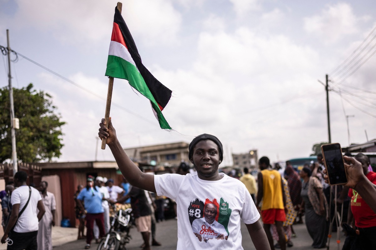 A supporter of Former Ghana President and presidential candidate of the National Democratic Congress (NDC) party John Mahama holds a flag of the party's colours as he celebrates in Accra on December 8, 2024. (Photo by OLYMPIA DE MAISMONT / AFP)
