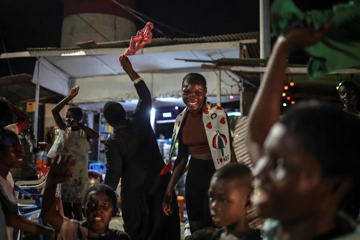 Supporters of former Ghana president and presidential candidate of the National Democratic Congress (NDC) party John Mahama cheer as they wait for results in front of a polling station in Accra on December 7, 2024 during the Ghana presidential and parliamentary elections. (Photo by OLYMPIA DE MAISMONT / AFP)
