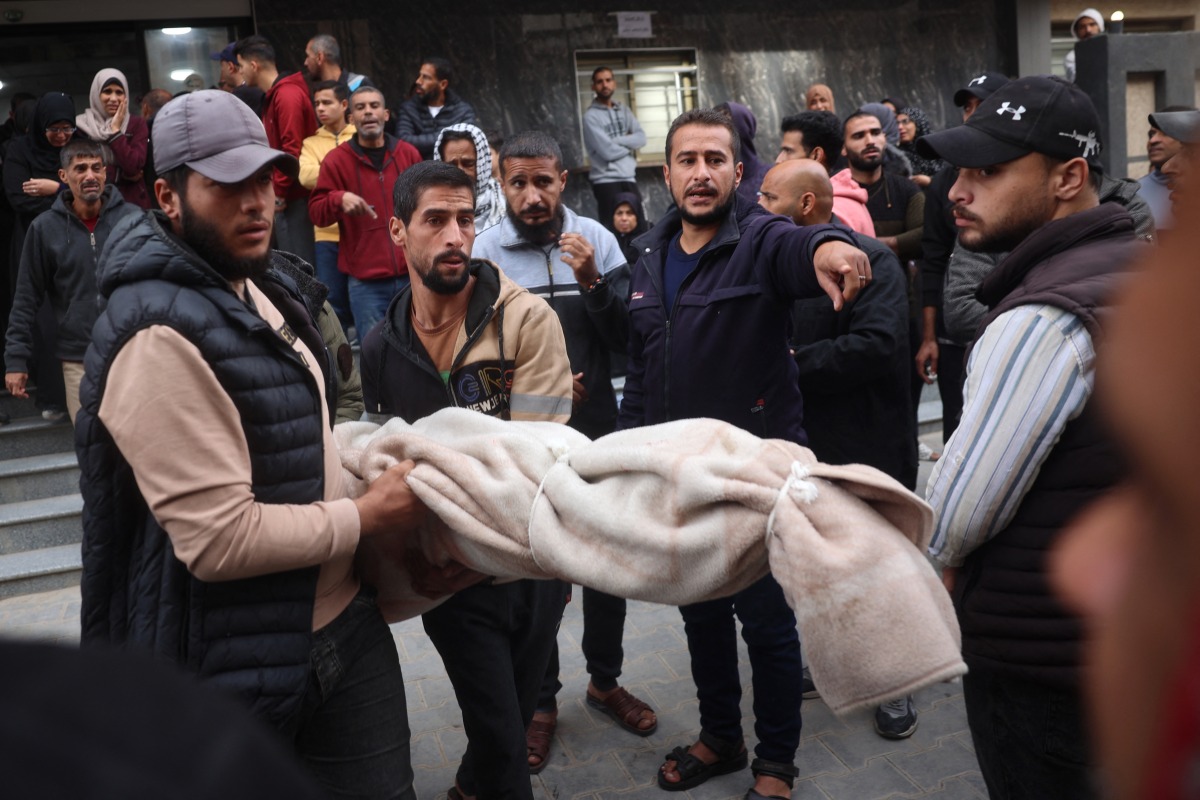 Palestinians carry a body as they prepare for a funeral at the al-Awda Hospital at the Nuseirat refugee Camp in the central Gaza Strip on December 7, 2024. (Photo by Eyad BABA / AFP)
