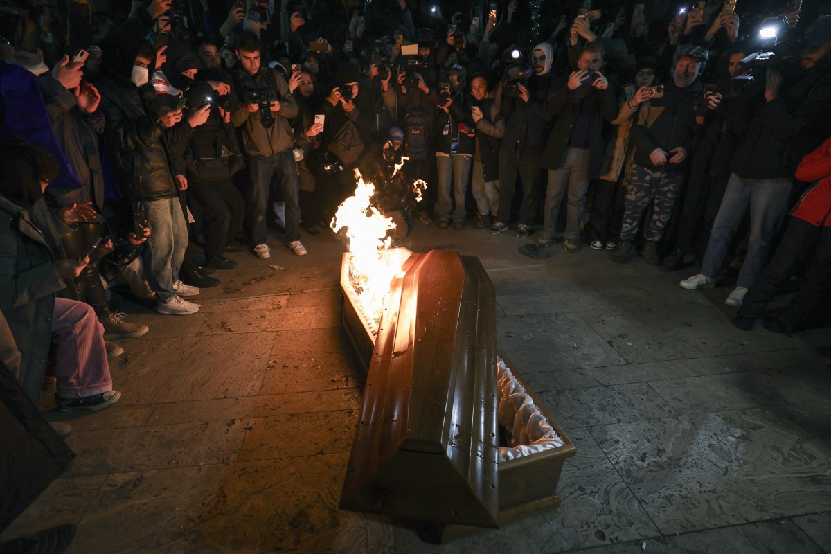 Photo used for representational purposes. Anti-government demonstrators take photographs of a coffin containing an image depicting Georgian billionaire Bidzina Ivanishvili as it burns after being set on fire during the twelfth consecutive day of mass protests against the government's postponement of EU accession talks until 2028, in central Tbilisi on December 9, 2024. Photo by Giorgi ARJEVANIDZE / AFP