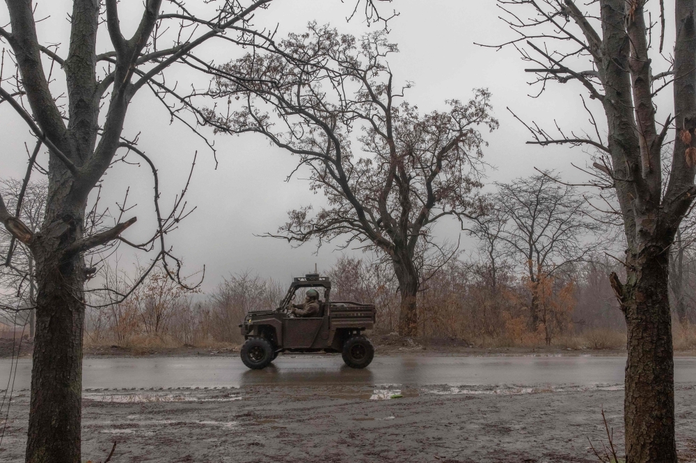 A Ukrainian soldier drives a vehicle on a road leading to the town of Chasiv Yar, in Kostyantynivka, eastern Donetsk region, on December 10, 2024. (Photo by Roman Pilipey / AFP)