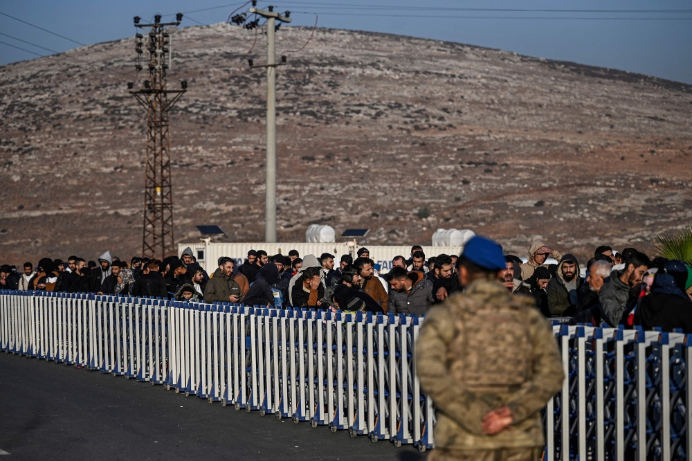 Syrian who lives in Turkey wait in a queue at Cilvegozu crossborder gate before entering in Syria at Reyhanli district in Hatay, on December 9, 2024. (Photo by Ozan Kose / AFP)

