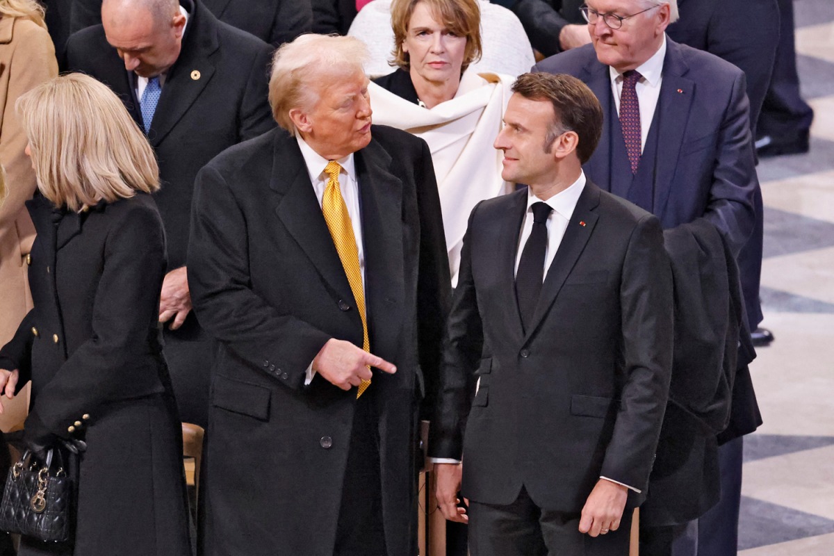 French President Emmanuel Macron (R) and US President-elect Donald Trump (C) speak ahead of a ceremony to mark the re-opening of the landmark Notre-Dame Cathedral, in central Paris, on December 7, 2024. (Photo by Ludovic Marin / Pool / AFP)