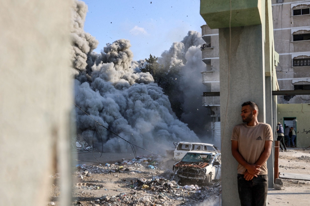 File: A man takes cover behind a column as an explosion propagates smoke and dust during an Israeli strike which reportedly targeted a school in the Zeitoun district on the outskirts of Gaza City, on September 1, 2024. (Photo by Omar Al-Qattaa / AFP)