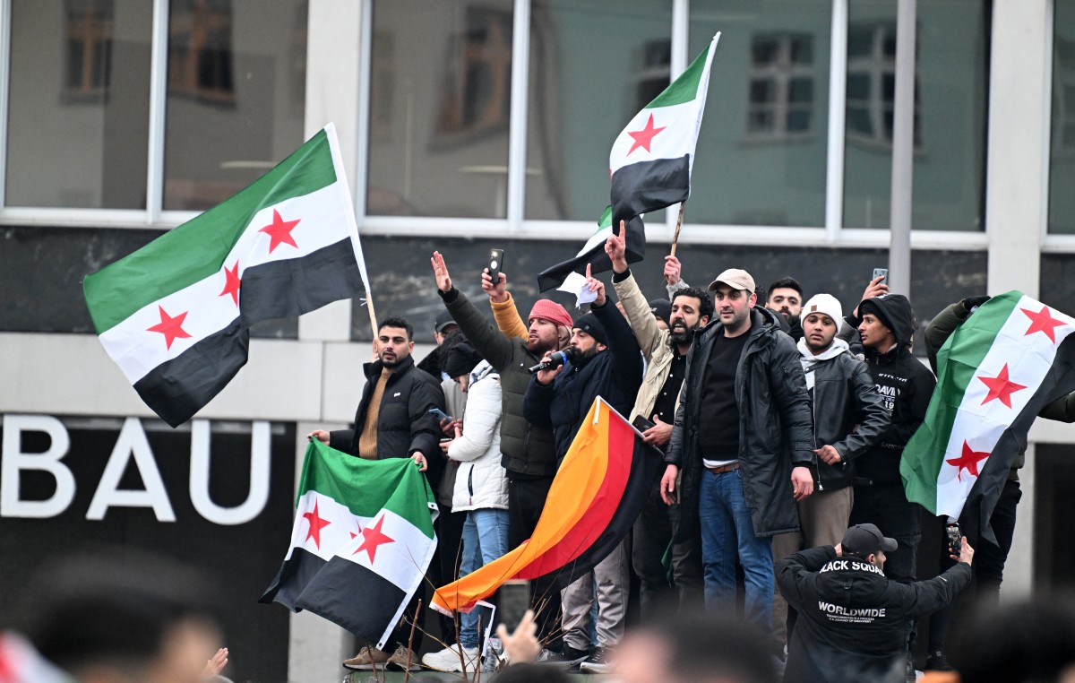 Members of the Syrian community hols flags of Syria and Germany as they rally on December 8, 2024 in Berlin, Germany, to celebrate the end of Syrian dictator Bashar al-Assad's rule after rebel fighters took control of the Syrian capital Damascus overnight. Islamist-led rebels toppled Syria's longtime ruler Bashar al-Assad in a lightning offensive that a UN envoy called 