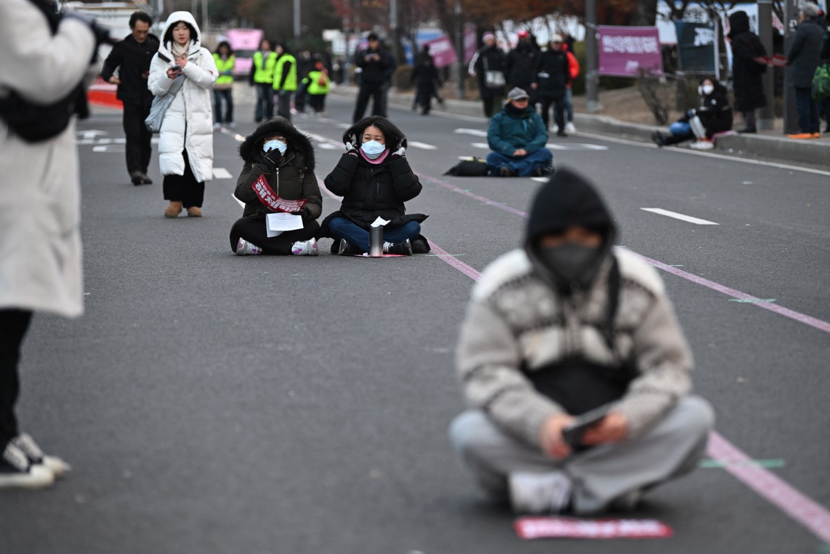 Demonstrators sit on a road as they take part in a protest calling for the ouster of South Korea President Yoon Suk Yeol on a road near the National Assembly in Seoul on December 13, 2024. Photo by Jung Yeon-je / AFP.
