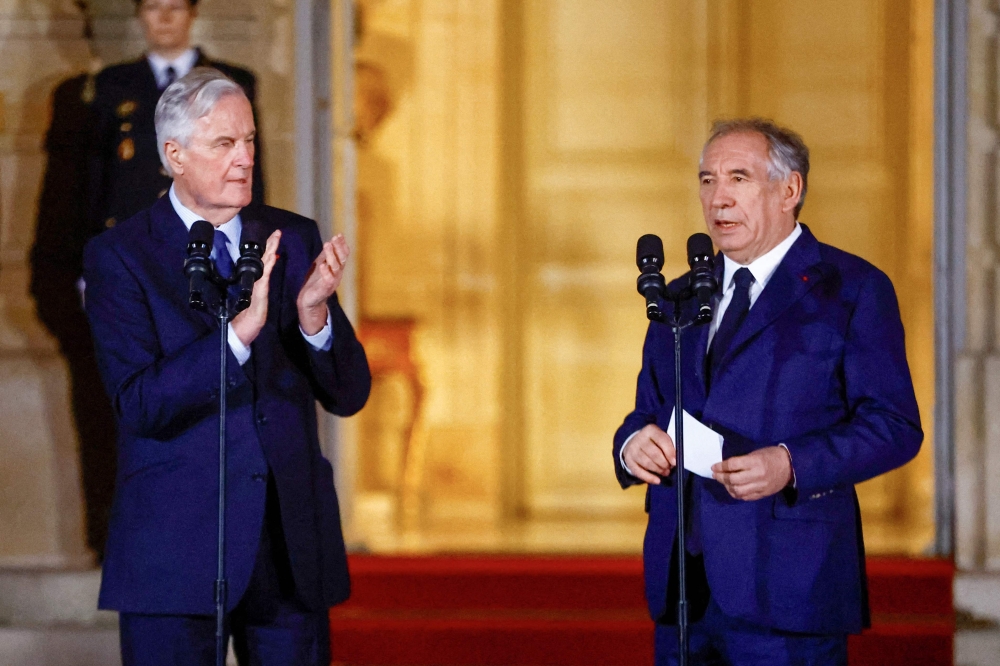 France's outgoing Prime minister Michel Barnier (left) applauds newly-appointed Prime Minister and President of the Democratic Movement (MoDem) party Francois Bayrou (right) during a handover ceremony at the Hotel Matignon in Paris on December 13, 2024. (Photo by Abdul Saboor / POOL / AFP)