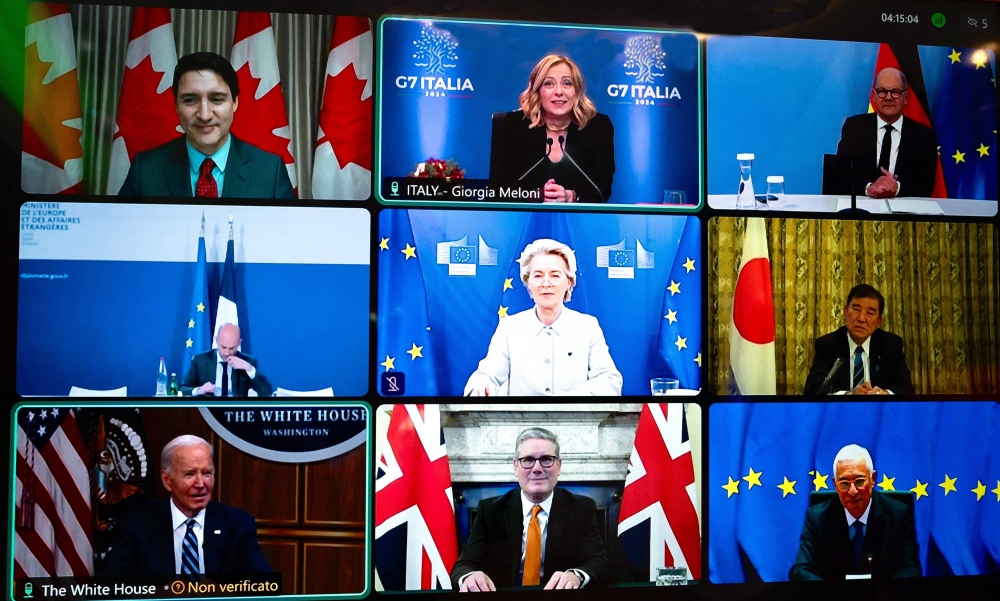 This handout picture taken in Rome and released on December 13, 2024 by Italy's Prime Minister press office (Palazzo Chigi Press Office), shows a screen displaying the G7 leaders meeting by video link. From top left : Canada's Prime Minister Justin Trudeau, Italy's Prime Minister Giorgia Meloni, Germany's Chancellor Olaf Scholz, France's France's Foreign Affairs Minister Jean-Noel Barrot, President of the European Commission Ursula von der Leyen, Japan's Prime Minister Shigeru Ishiba, US President Joe Biden, Britain's Prime Minister Keir Starmer and President of the European Council Antonio Costa. (Photo by Handout / Palazzo Chigi press office / AFP) 