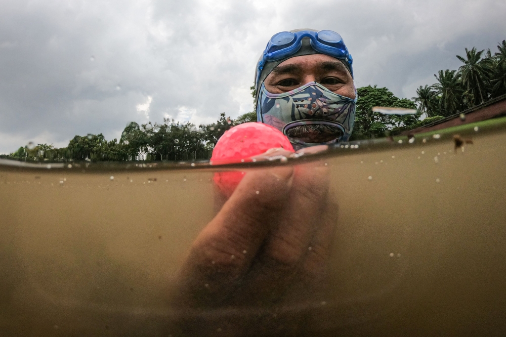 In this picture taken on November 11, 2024, Sumadi Ibrahim shows a golf ball he found inside a pond at a course in Shah Alam, on the outskirts of Kuala Lumpur. (Photo by Mohd Rasfan / AFP)