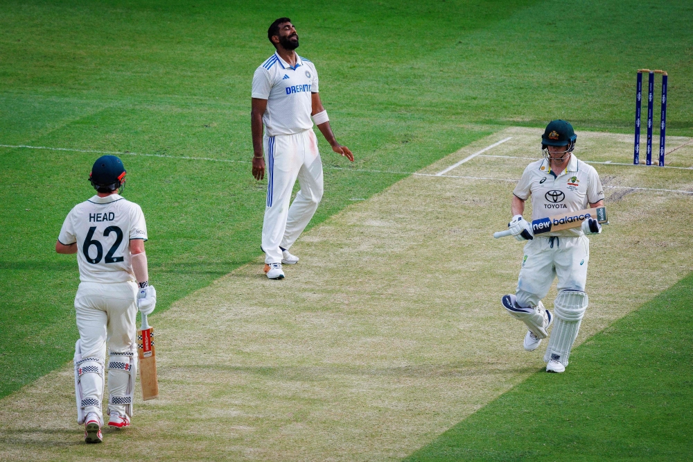 India's Jasprit Bumrah reacts after Australia's Travis Head (L) scores another boundary as Steve Smith (R) looks on during day two of the third cricket Test match between Australia and India at The Gabba in Brisbane on December 15, 2024. (Photo by Patrick Hamilton / AFP) 