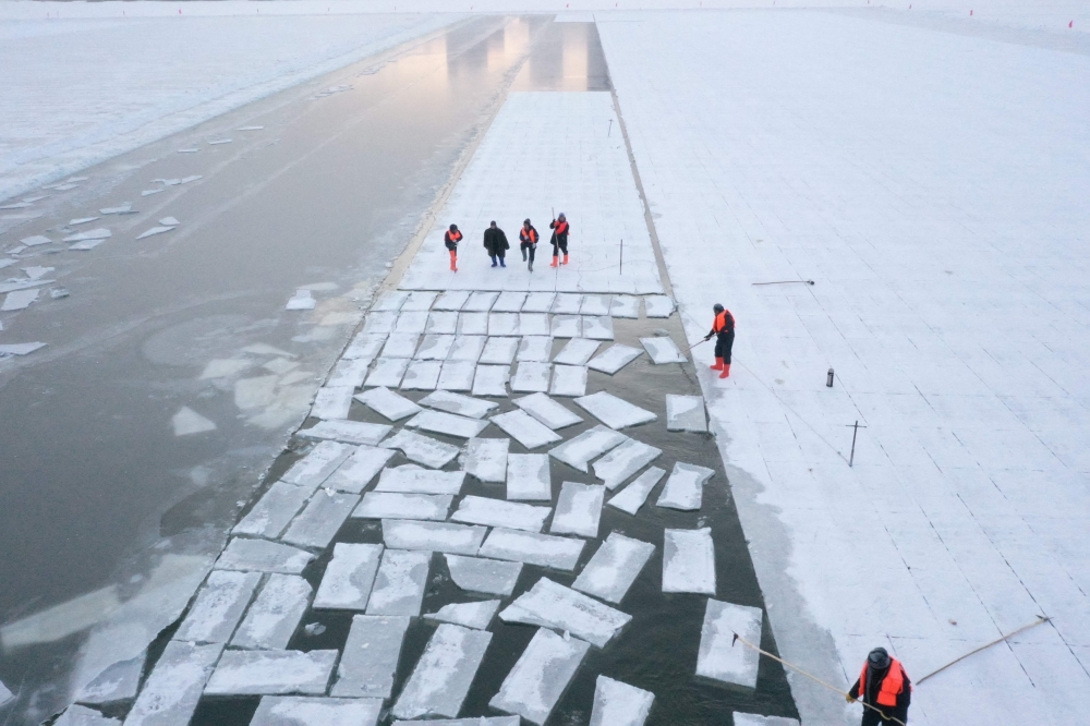 This aerial picture shows workers harvesting ice from the frozen Songhua river in preparation for the annual Harbin Ice and Snow World festival in Harbin, China's northeast Heilongjiang province on December 17, 2024. (Photo by Adek Berry / AFP)