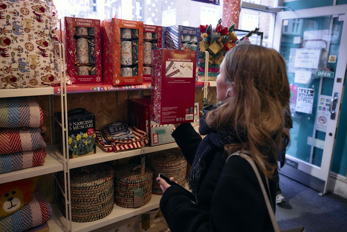 A customer browses Christmas crackers inside an Oxfam charity shop in London, on December 18, 2024. Photo by BENJAMIN CREMEL / AFP