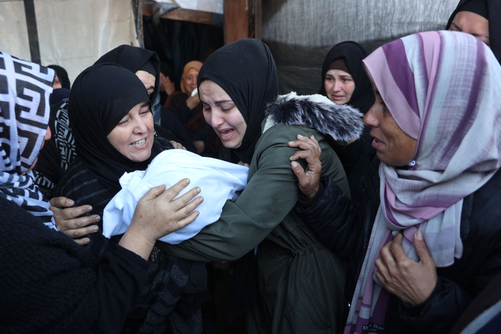 Palestinian women mourn a dead child, killed in an Israeli strike the previous night, at Al-Ahli Arab hospital, also known as the Baptist hospital, in Gaza City on December 21, 2024. (Photo by Omar Al-Qattaa / AFP)
 