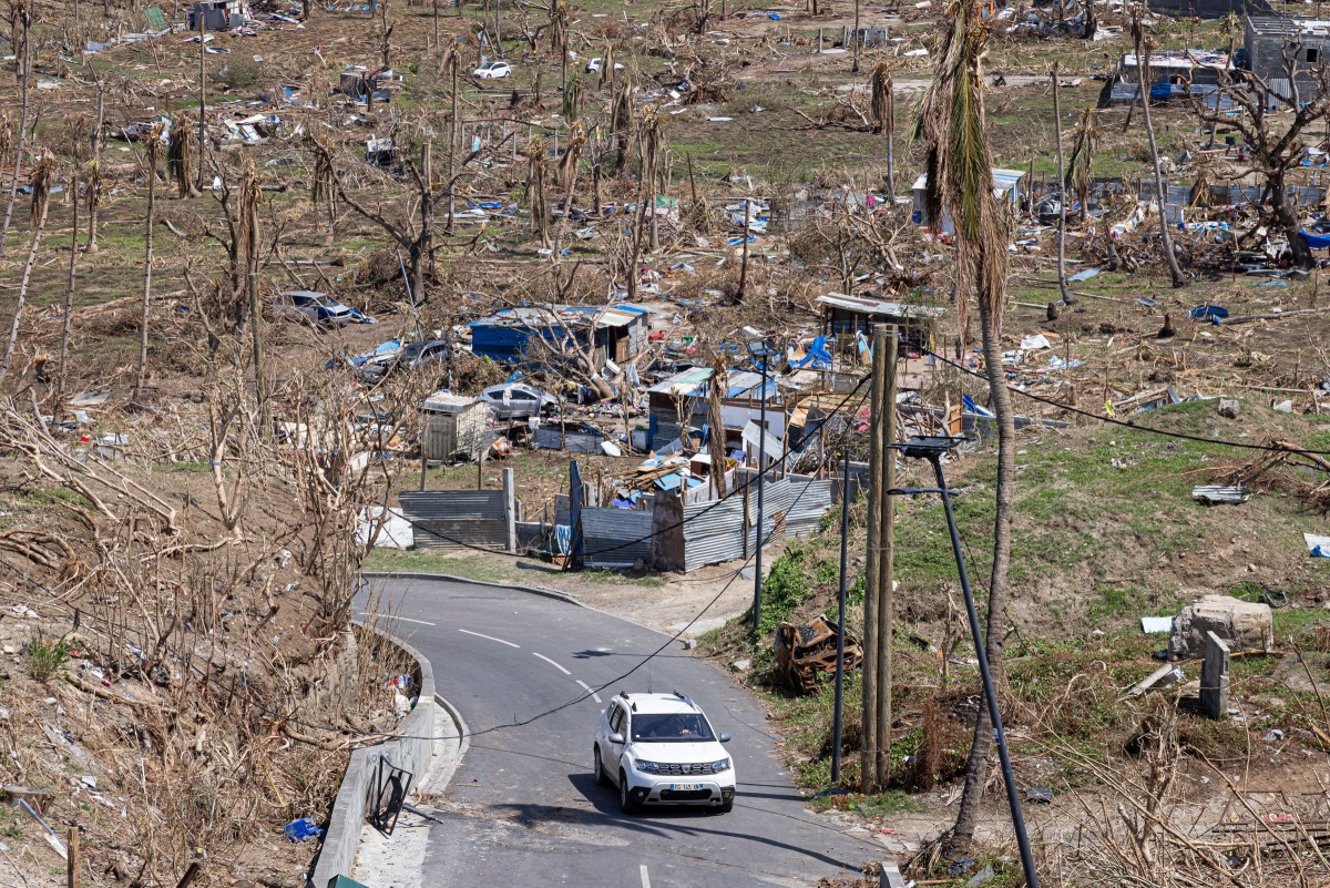 A car drives past destroyed homes in Pamandzi on the French Indian Ocean territory of Mayotte, after the cyclone Chido hit the archipelago on December 21, 2024. (Photo by PATRICK MEINHARDT / AFP)
