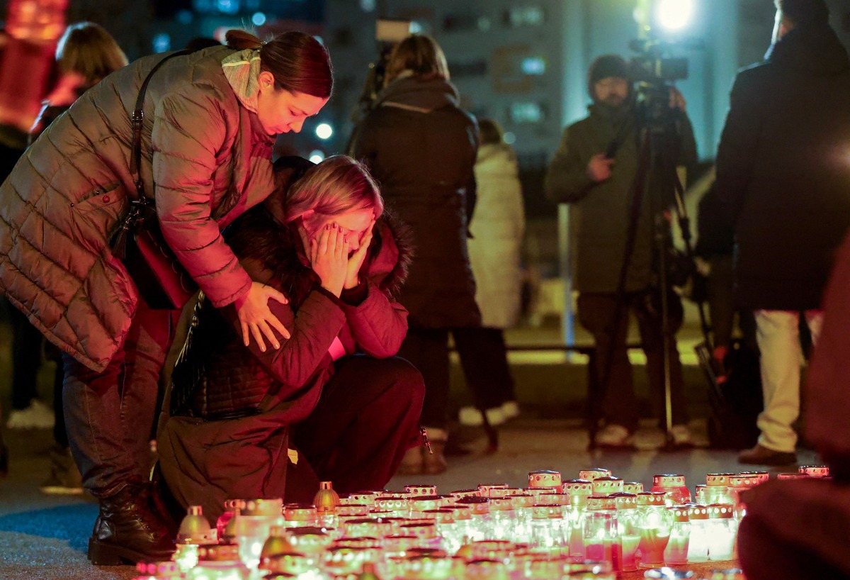 People react next to a makeshift memorial at the playground of Precko primary school, following a stabbing attack at the school which left one dead and several injured, in Zagreb, on December 20, 2024. (Photo by DAMIR SENCAR / AFP)
