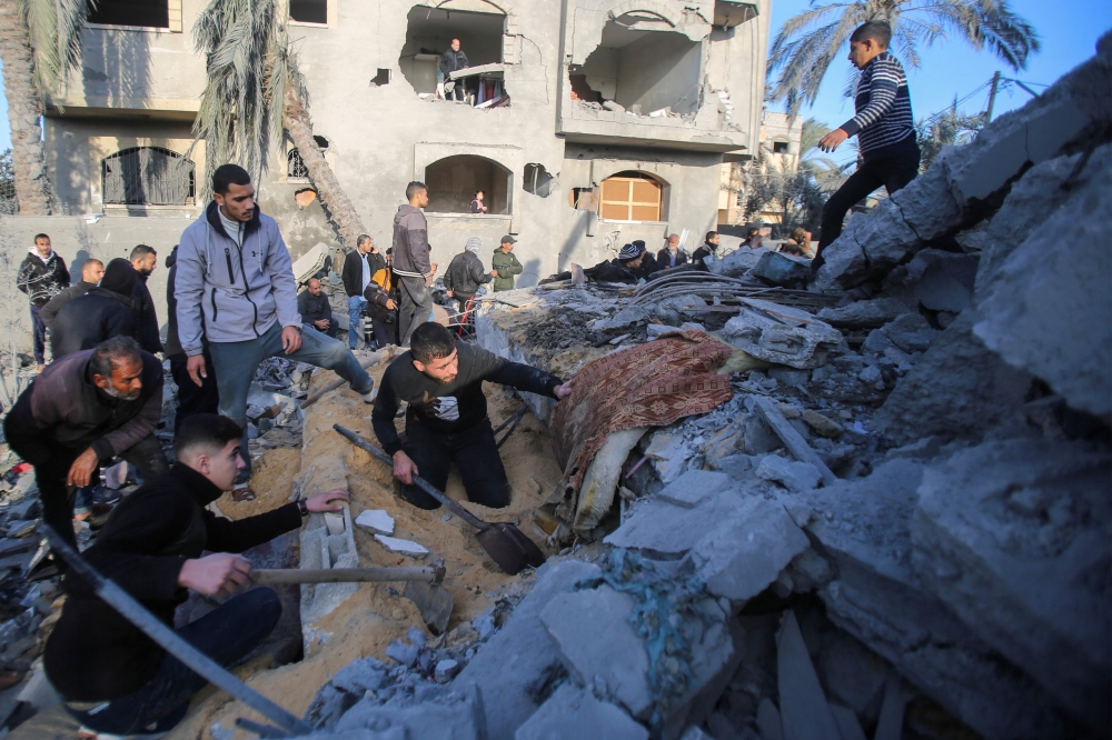 People search for survivors at the site of an Israeli strike that targeted the Abu Samra family home in Deir el-Balah in the central Gaza Strip on December 22, 2024. (Photo by Eyad Baba / AFP)