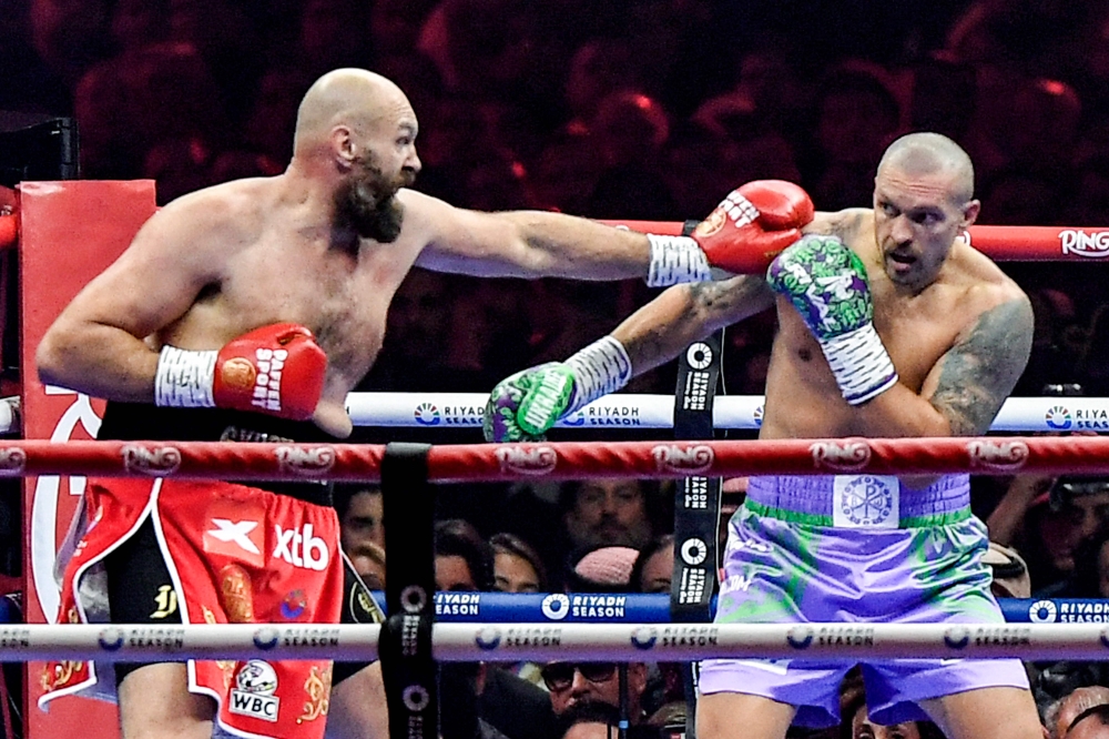 Britain's Tyson Fury (red) and Ukraine's Oleksandr Usyk (blue) compete during their heavyweight world championship rematch at the Kingdom Arena in Riyadh on December 22, 2024. (Photo by AFP)