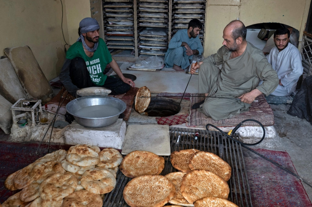 Afghan baker Jamil Ghafori (L) preparing traditional flatbreads locally known as Naan, at a bakery in Kabul. (Photo by Wakil Kohsar / AFP)