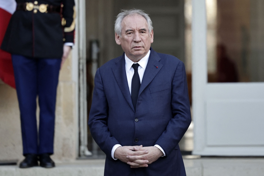 France's Prime Minister Francois Bayrou stands at attention as he observes a minute of silence as part of an official day of mourning for the victims of Cyclone Chido at The Hotel Matignon in Paris on December 23, 2024. (Photo by Stephane De Sakutin / AFP)