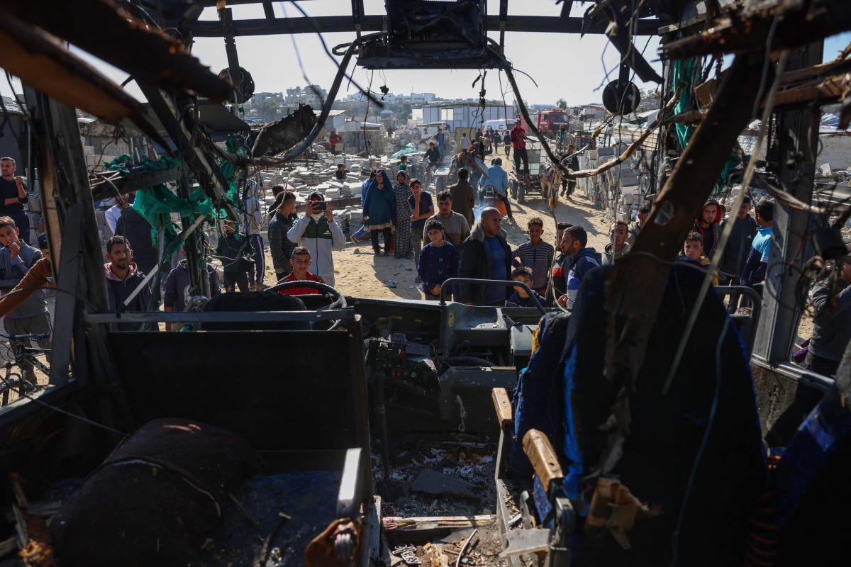 People gather around a bus hit by an Israeli strike which led to casualties, in the Mawasi area west of Khan Yunis city in the southern Gaza Strip on December 23, 2024. Photo by BASHAR TALEB / AFP