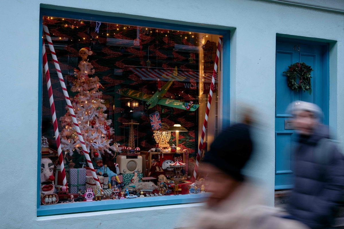 Pedestrians pass Christmas items displayed in the window of 43 Camden Passage, owned by Bob Borzello, in London on December 20, 2024. Photo by BENJAMIN CREMEL / AFP