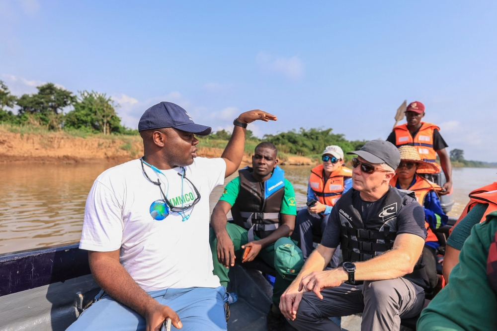 Aristide Takoukam Kamla (L), a marine biologist, researcher and conservationist specialising in the African manatee, talks to tourists and other biologists on a boat in Dizangue, on December 10, 2024. (Photo by Daniel Beloumou Olomo / AFP)