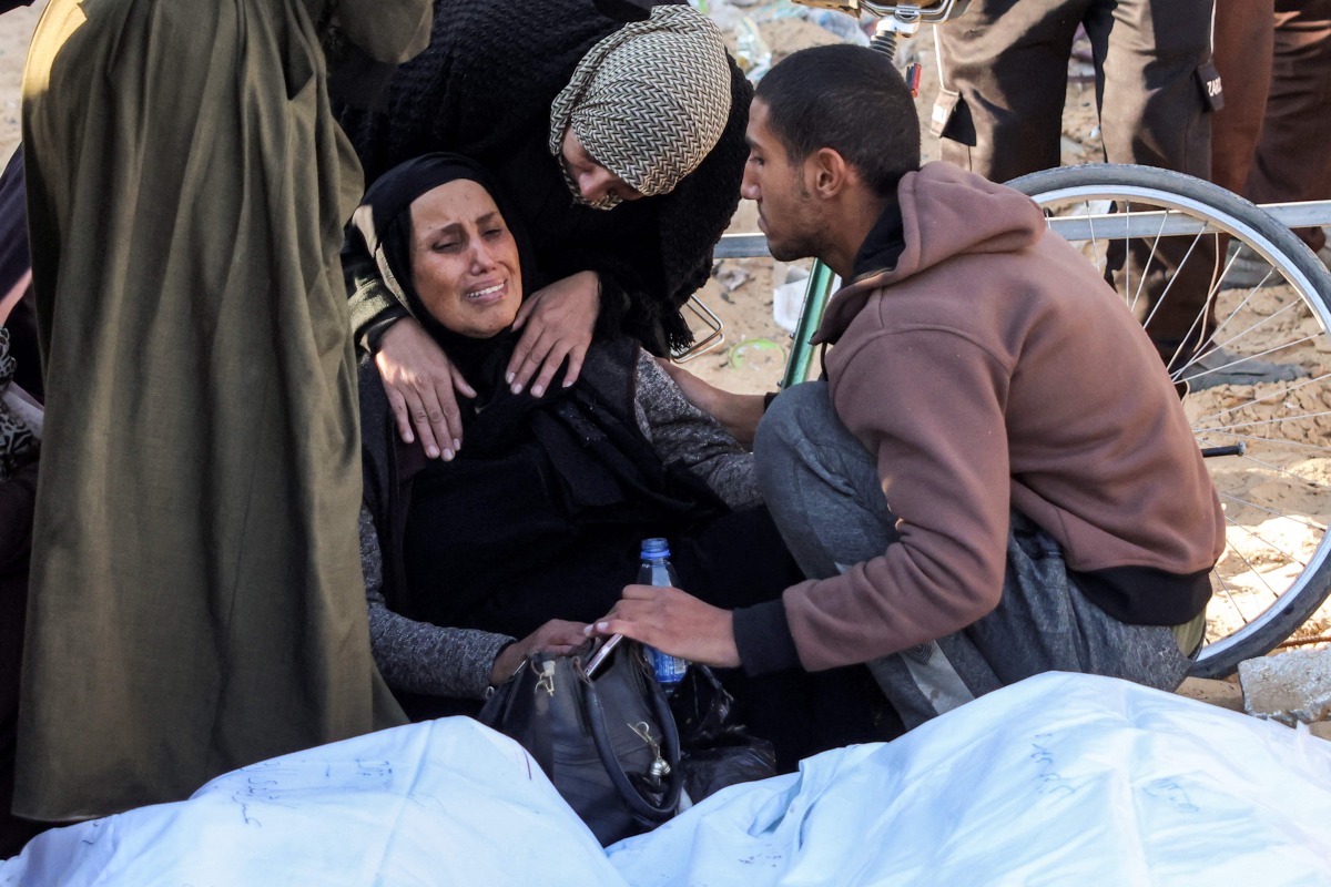 A woman is comforted as she mourns by the body of one of the martyrs killed in overnight Israeli bombardment outside the morgue of Nasser Medical Complex in Khan Yunis in the southern Gaza Strip on December 23, 2024 (Photo by BASHAR TALEB / AFP)
